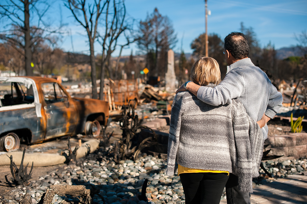 Couple looking at remains of their home after wildfire